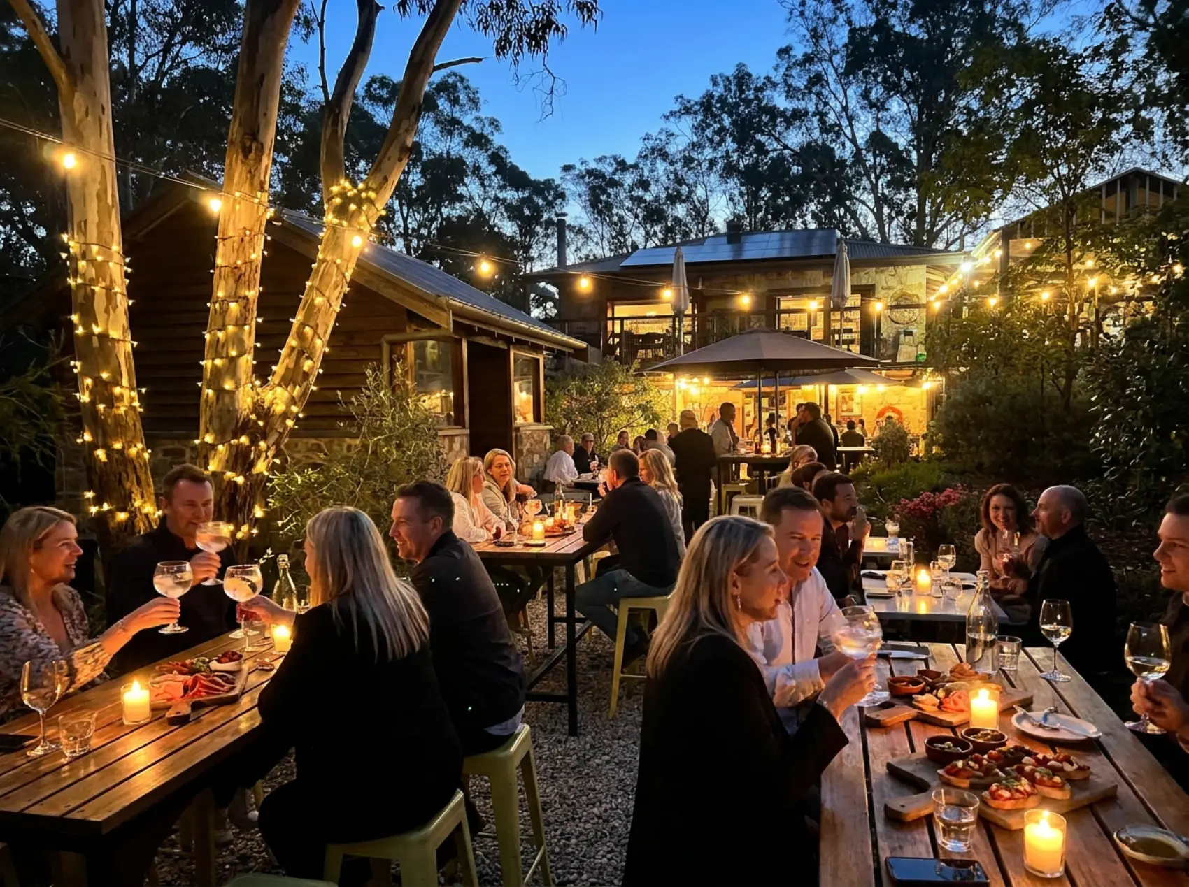 Outdoor tables under festoon lights at Three Little Birds Distillery at dusk